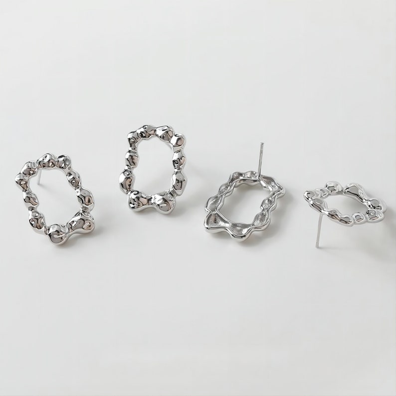 May include: Three silver earrings with a unique, organic, and textured oval shape. The earrings are designed with a post back.