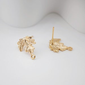 May include: A pair of gold-tone leaf-shaped earring findings with a loop at the bottom. The findings are designed to be used with a variety of earring styles.