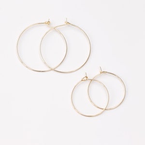 May include: Two pairs of gold hoop earrings. The larger pair is about 2 inches in diameter, and the smaller pair is about 1 inch in diameter.