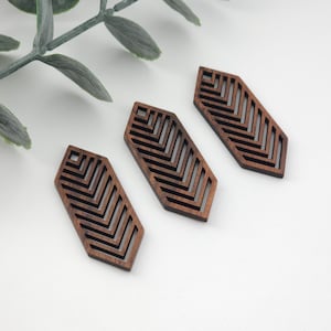 May include: Three wooden geometric shapes with a chevron pattern cut out. The shapes are dark brown and have a slightly rough texture.