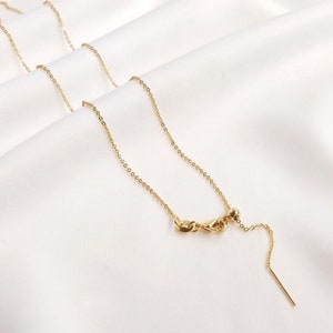 Peut inclure: Un collier en cha&icirc;ne dor&eacute;e avec un fermoir coulissant et une petite perle &agrave; l'extr&eacute;mit&eacute;. La cha&icirc;ne est d&eacute;licate et a un &eacute;clat subtil.