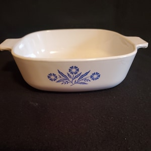 May include: White baking dish with blue floral design. The dish has two handles on the sides.