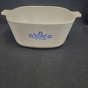 May include: White ceramic baking dish with blue floral design. The dish has two handles on the sides.