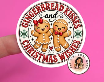May include: A circular sticker featuring two smiling gingerbread cookies, one with a red bow and one with a red bowtie, surrounded by the text GINGERBREAD KISSES and CHRISTMAS WISHES in red, with green snowflakes and a small red heart.
