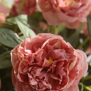 May include: A bouquet of pink peonies with green leaves. The peonies are in full bloom and have a delicate, ruffled texture.