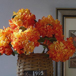 May include: A bouquet of orange and yellow silk flowers in a wicker basket with the number 1995 on a tag.