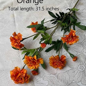Puede incluir: Tallo de flores artificiales de color naranja con m&uacute;ltiples flores. Las flores son de color naranja intenso y tienen un aspecto arrugado. Los tallos son verdes y tienen hojas. Longitud total: 80 cm.