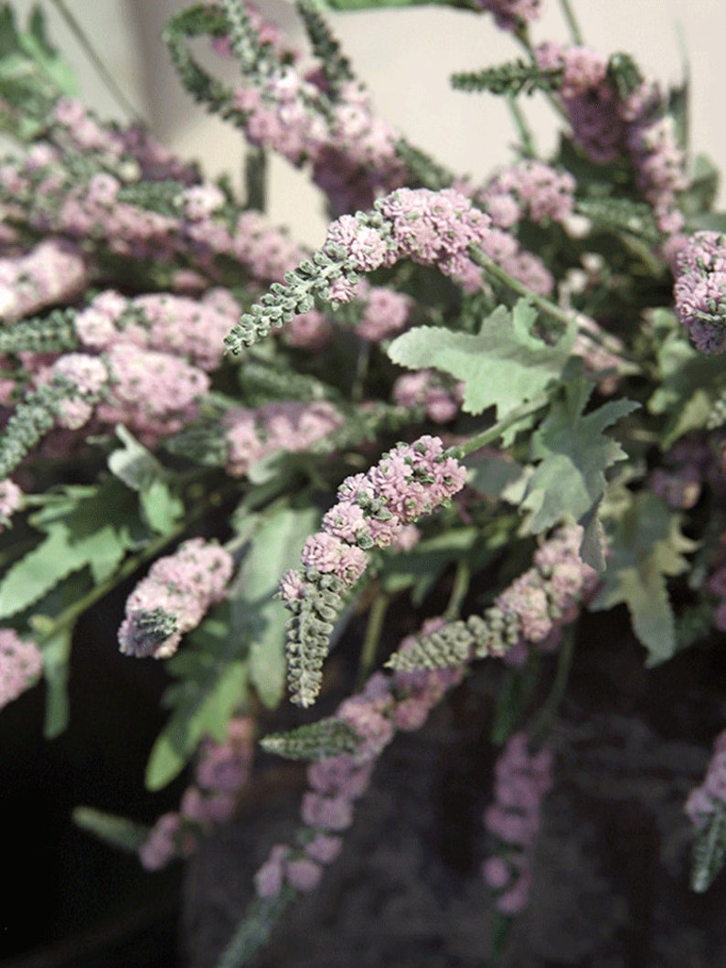 Puede incluir: Un ramo de flores de lavanda artificiales con tallos y hojas verdes. Las flores son de color morado claro y est&aacute;n dispuestas en un racimo.