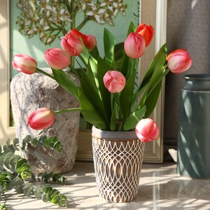 Könnte beinhalten: Ein Strauß rosa und roter Tulpen in einer weißen und braunen, gemusterten Keramikvase. Die Vase hat ein geometrisches Design.