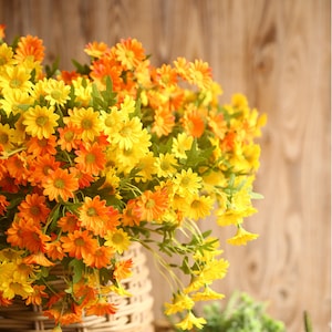 May include: A bouquet of artificial flowers with yellow and orange daisy-like blooms. The flowers are arranged in a wicker basket.