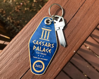 May include: A blue and gold Caesars Palace Las Vegas key tag with a silver key attached. The tag reads "Villa Suite" and "Caesars Palace Las Vegas" with the number 2452. The text "Tiger Not Included" is also visible.