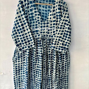 Puede incluir: Vestido de manga larga con cuello en V, con un estampado de puntos azul oscuro sobre fondo azul claro. El vestido est&aacute; colgado en una percha de madera. El texto "indiankanthakimono" es visible en el vestido.