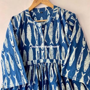 May include: A blue cotton dress with a white fish print and white polka dots. The dress has a button-up front and a gathered waist.