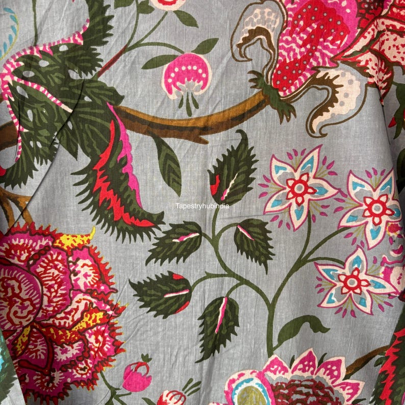 May include: A close-up of a gray fabric with a floral pattern. The flowers are pink, red, blue, and green. The fabric has a textured surface.