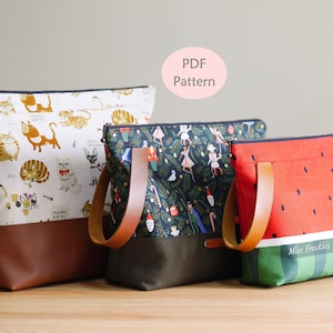 May include: Three zipped pouches with brown leather-look handles. The left pouch features a white cat print, the middle has a dark green holiday pattern, and the right is a red and green watermelon design with the text Miss Freckles Design.