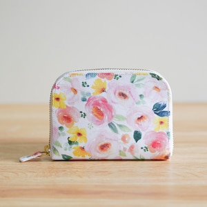 May include: A white zippered pouch with a floral print featuring pink, yellow, and green flowers.