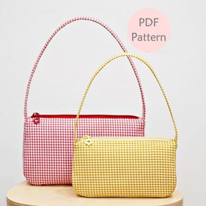 Puede incluir: Dos bolsos de mano de tela vichy, uno rojo y blanco y otro amarillo y blanco. Ambos bolsos son pequeños y tienen una sola correa.