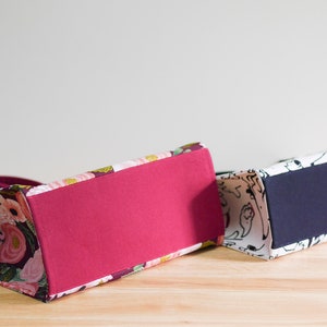 Pu&ograve; includere: Due borse tote con motivi diversi. La borsa a sinistra ha un motivo floreale con fiori rosa, bianchi e verdi su uno sfondo bordeaux. La borsa a destra ha un motivo bianco e nero con forme astratte. Entrambe le borse hanno un fondo di colore pieno.