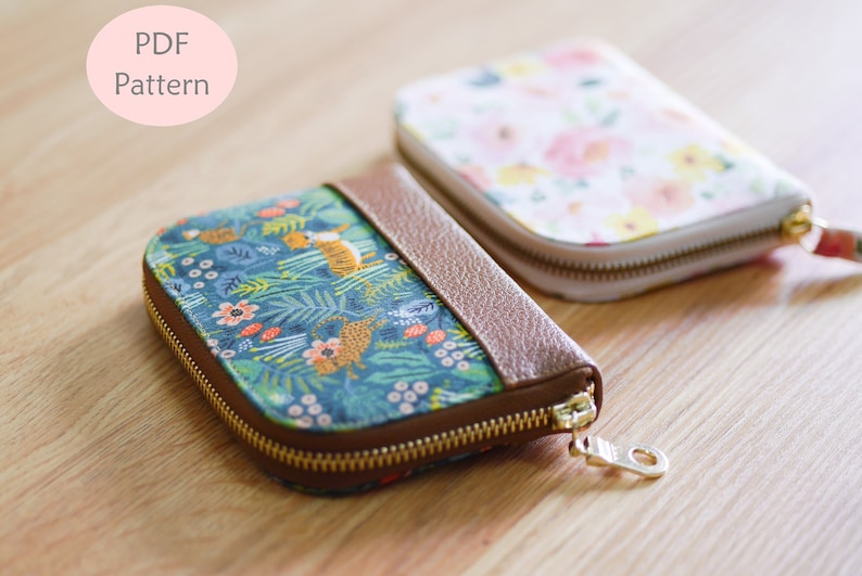 May include: Two zippered pouches with different fabric patterns. One pouch has a brown leather trim and a floral pattern. The other pouch has a blue background with a jungle animal print. The text "PDF Pattern" is visible in the top left corner of the image.