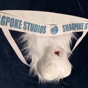 May include: White furry jockstrap with a blue and white elastic band that says "Shagpoke Studios".