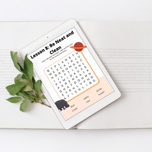 Può includere: Un tablet che mostra un cruciverba con le parole "Be Neat and Clean" e un ippopotamo dei cartoni animati. Il cruciverba è su uno sfondo rosa e arancione con un pianeta dei cartoni animati nell'angolo in alto a destra.