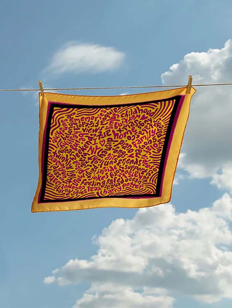 May include: A yellow silk scarf with a black border and pink lettering. The lettering is in a swirling pattern and includes words like "memories", "love", "friends", and "ocean".