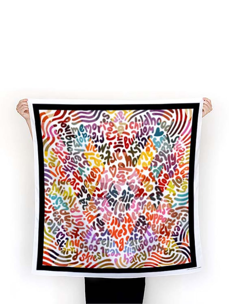 May include: A white square scarf with a black border. The scarf is covered in colorful, handwritten words, including "memories", "childhood", "jokes", "safe", "ocean", "skies", "ideas", "love", "friends", "family", "air", "sun", "moon", "stars", "feeling", "happy", "harry potter", and more.