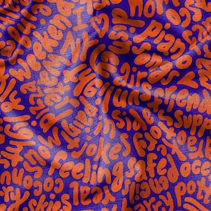 May include: A blue fabric background with orange text printed on it. The text is in a variety of fonts and sizes and includes words like "ideas", "weekend", "friends", "safe", "jokes", "feeling", "ocean", and "love".