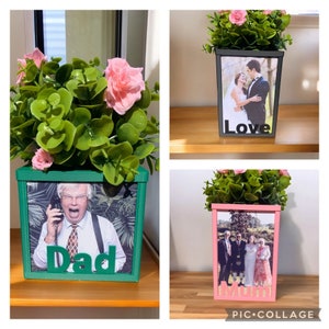 Può includere: Tre cornici per foto con basi in legno dipinte di verde, nero e rosa. Ogni cornice contiene una foto diversa e una parola sotto la foto. Le parole sono "Papà", "Amore" e "Mamma".