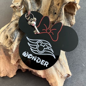 Könnte beinhalten: Schwarzer und roter Schlüsselanhänger in Form einer Minnie Mouse mit einem weißen Disney Cruise Line Logo und dem Wort "WONDER" in weiß. Der Schlüsselanhänger hat einen silbernen Schlüsselanhänger.