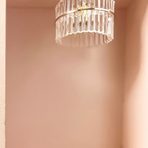 May include: A gold ceiling light fixture with a clear glass shade made of vertical glass rods. The light fixture is mounted on a white ceiling.