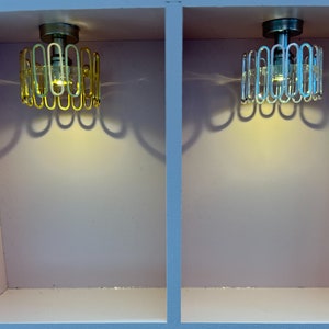May include: Two ceiling light fixtures with circular metal shades. The shade on the left is gold and the shade on the right is silver.