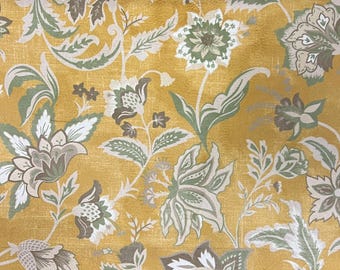 Puede incluir: Primer plano de un estampado floral con grandes flores y follaje estilizados en tonos verdes, crema y marrón sobre un fondo amarillo dorado. El diseño tiene una apariencia texturizada, con una estética vintage o antigua.