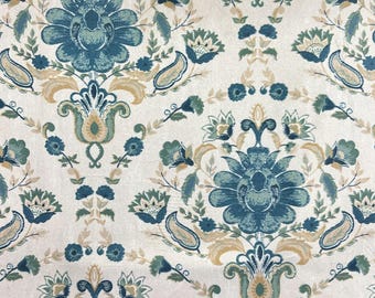 May include: A close-up of a fabric with a repeating floral pattern. The design features large, stylized blue flowers with green and tan accents on a cream background. The pattern is symmetrical and ornate.