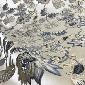 May include: White fabric with a floral pattern in shades of gray and beige. The fabric has a textured, woven look.