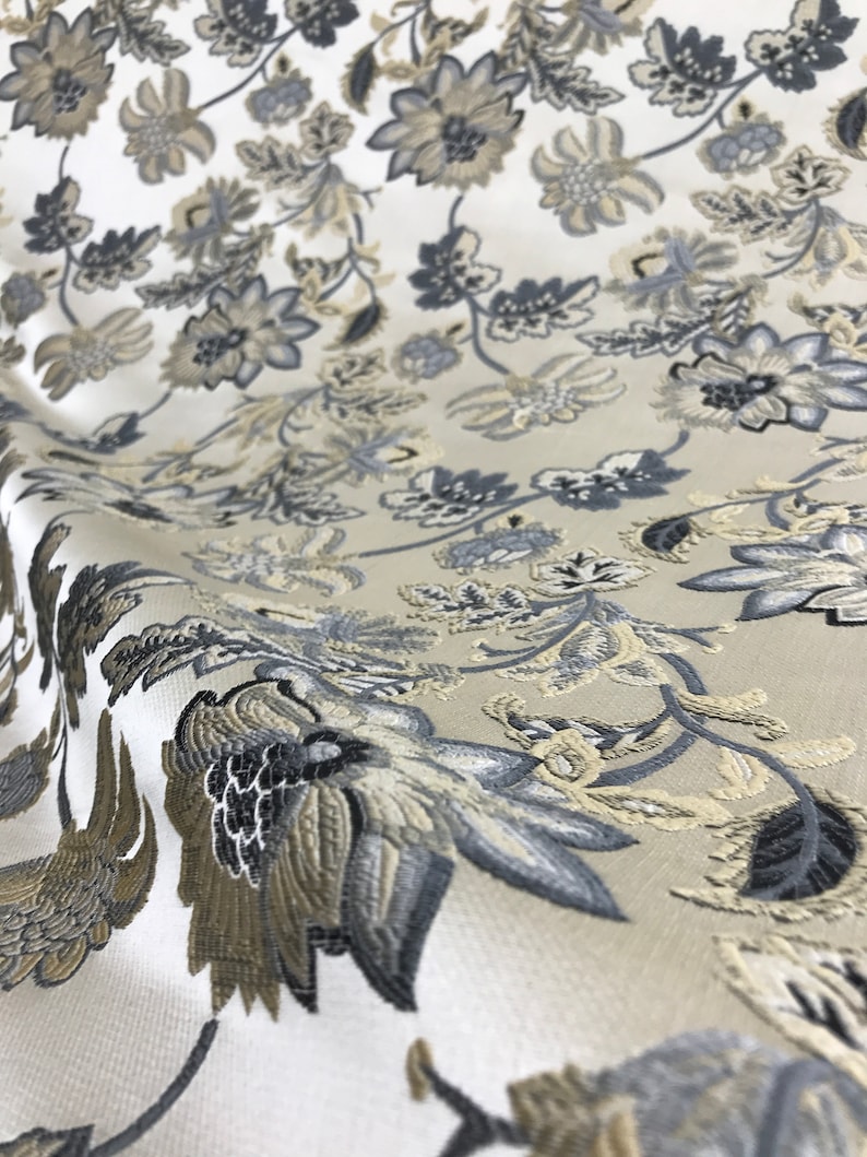 May include: White fabric with a floral pattern in shades of gray and beige. The fabric has a textured, woven look.