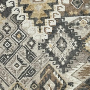 May include: Close-up of a patterned textile featuring a geometric design in shades of gray, brown, and beige. The pattern includes diamond, square, and triangular shapes, creating a textured appearance. The textile has a woven look.