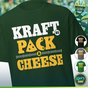 May include: Green t-shirt with the words "KRAFT PACK & CHEESE" in white and yellow. The number "85" is above the word "PACK". The shirt has a crew neck and short sleeves. Additional shirt colors are shown in the image.