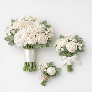 May include: Three crochet bouquets and a buttonhole. The bouquets feature white roses and small white flowers with green leaves. The stems are wrapped in green yarn and white satin ribbon. The buttonhole is tied with twine.