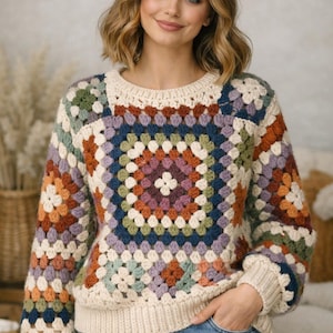 May include: A colourful, crocheted sweater with a granny square design. The sweater features a cream-coloured base with a square pattern of various colours, including orange, blue, green, and purple. The sleeves and neckline are cream-coloured.