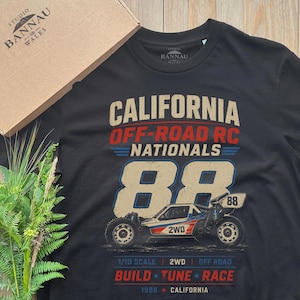 Könnte beinhalten: Ein schwarzes T-Shirt mit einem Grafikdruck, der CALIFORNIA OFF-ROAD RC NATIONALS 88 liest, einer Abbildung eines 2WD Offroad-RC-Autos und dem Text 1/10 SCALE 2WD OFF ROAD BUILD TUNE RACE 1988 CALIFORNIA.