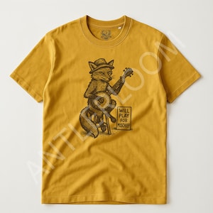 May include: Mustard yellow t-shirt featuring a fox playing a banjo. The fox is wearing a hat and sitting on a stool. The text "WILL PLAY FOR MISCHIEF" is below the fox. The shirt has a crew neck and short sleeves.