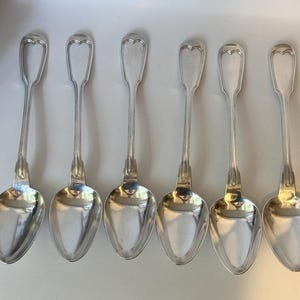 May include: Six silver spoons with ornate handles. The spoons have a classic design and are in excellent condition.