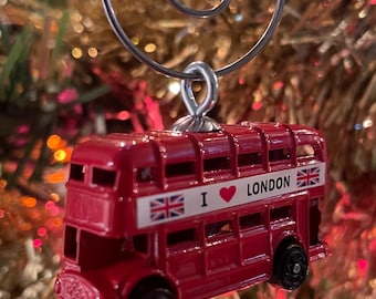 Puede incluir: Adorno de Navidad de autobús de dos pisos rojo con un letrero blanco "I love London" y una bandera de la Union Jack en el lateral.