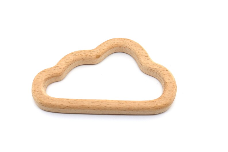Puede incluir: Un mordedor de madera en forma de nube para beb&eacute;s. El mordedor est&aacute; hecho de madera natural y tiene una superficie lisa y redondeada.