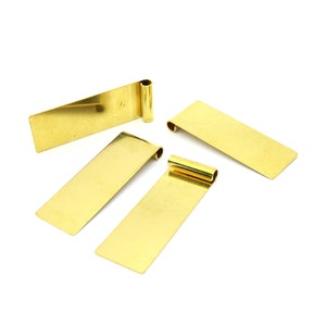 Può includere: Quattro linguette segnalibro in metallo dorato con bordi arrotondati e un'estremità arrotolata. Le linguette sono disposte a semicerchio su uno sfondo bianco.