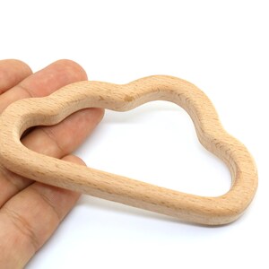 Puede incluir: Un juguete de madera en forma de nube para beb&eacute;s y ni&ntilde;os peque&ntilde;os. El anillo est&aacute; hecho de madera natural y tiene una superficie lisa y redondeada.