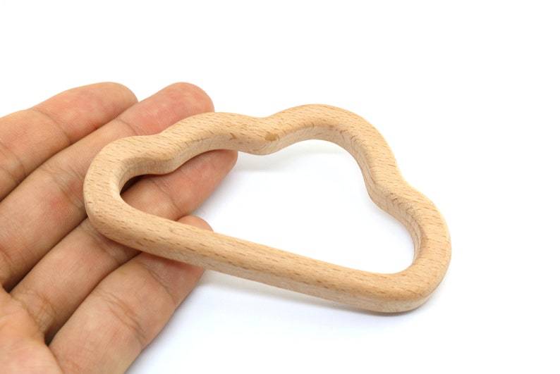 Puede incluir: Un juguete de madera en forma de nube para beb&eacute;s y ni&ntilde;os peque&ntilde;os. El anillo est&aacute; hecho de madera natural y tiene una superficie lisa y redondeada.