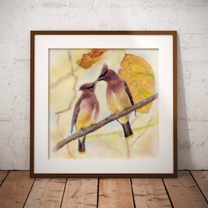 May include: Watercolor painting of two cedar waxwings perched on a branch with autumn leaves. The birds are facing each other, with one bird's beak touching the other's. The painting is framed in a brown wood frame.