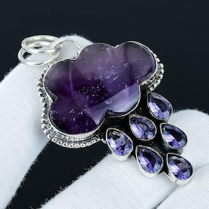 May include: A silver pendant featuring a purple amethyst cloud with smaller amethyst drops hanging below. The pendant is on a white surface.